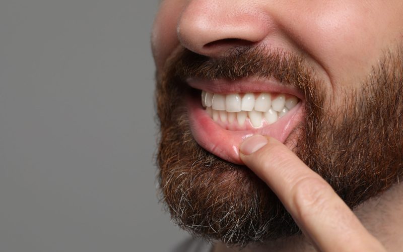 Man showing healthy gums on gray background, closeup. Space for text